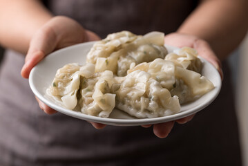 Steamed dumpling filled with pork and vegetables on dish holding by hand
