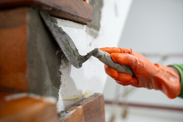 A person is using a trowel to apply cement to a wall.
