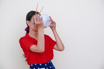 Asian woman sipping her last drop of Chinese noodle from the bowl