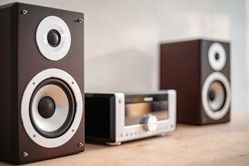 Two modern bookshelf speakers flank a sleek radio receiver, all set against a minimalist backdrop....