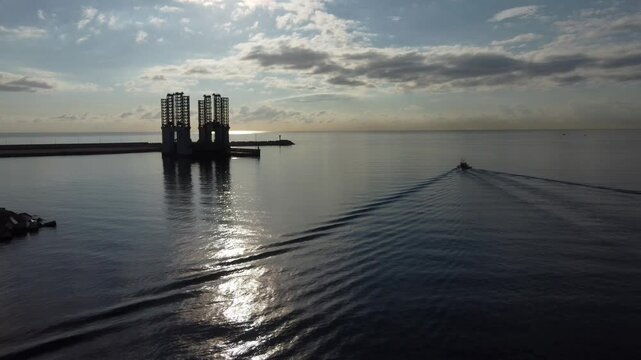 Aerial tracking of a fishing boat exiting the port. Backlighted floating dock for engineering projects.