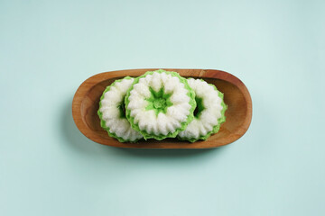 Putu Ayu is served on a wooden plate with green background. It is a traditional dessert made from steamed rice flour and topped with grated coconut, a classic Indonesian cake