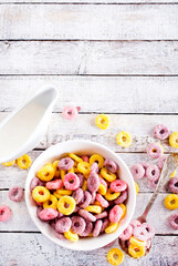 Falling colorful corn rings into bowl on white table