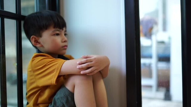 A sad young boy sat in the corner crying and covering her face with her hands. The concept of child abuse in the family Parents punish their children into a corner, the child is depressed, crying, lif