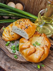 Pies with green onions and egg on a wooden background