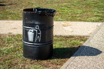 A trash can with a black lid and a black trash bag on top