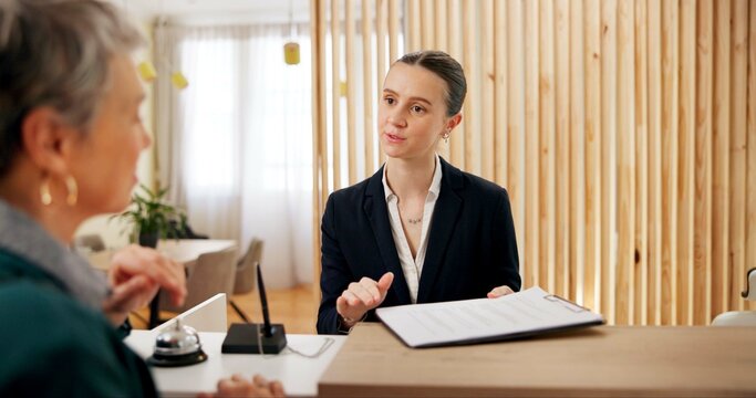 People, client and receptionist in hotel with clipboard, booking information and checklist on counter. Help desk, hospitality and concierge with mature customer for service, assistance or reservation