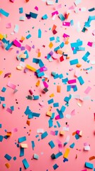 Colorful confetti scattered on a pink background, perfect for celebrations.