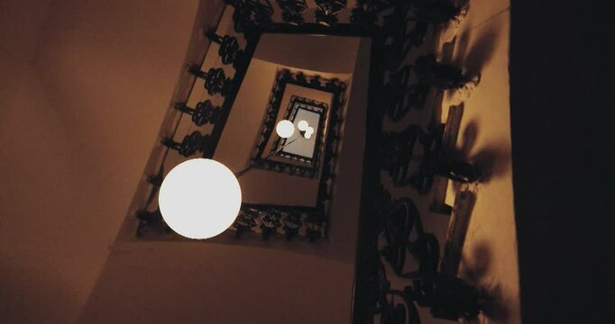 Beautiful slow motion shot with contrapicado angle of a staircase inside an elegant enclosure and a circular house spotlight.