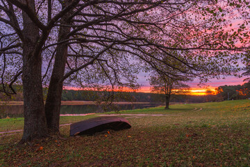 Experience the Serene Sunset by the Water, Surrounded by Colorful Autumn Leaves and a Peaceful Boat