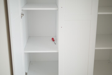 A completely empty white cabinet elegantly showcases a lone screwdriver, neatly tucked inside