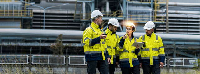 Male and female industrial engineers wearing hard hats talk to collaborate on new project. Team of...