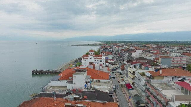 Tourists walk along the sandy shores and pier of Paralia Katerinis, a vibrant summer destination on the Aegean Sea, enjoy Greek atmosphere and scenic coastal views