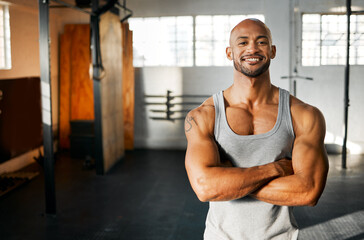 Portrait, fitness and happy man with arms crossed in gym for workout, body health and wellness. Face, smile and confident African bodybuilder, personal trainer and strong athlete with muscle in Kenya