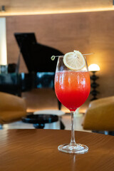 Premium Alcoholic Cocktail with blurred music band as background,Pleasant Evening In Respectable Restaurant With Cocktail,close up of wine glass on wooden table with blurry bar background scene.