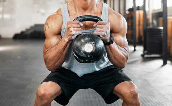 Bodybuilder, hands and squat for kettlebell, exercise or workout for arm strength at gym. Man training, weights and sports athlete for weightlifting, muscle power and health club fitness performance
