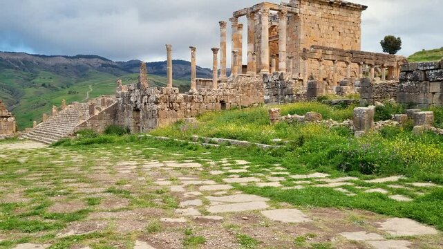 Revealing shot of Roman Severan temple and columns in archaeological site of Djemila Algeria on cloudy day