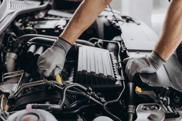 Fototapeta premium Close-up shot of unrecognisable man wearing gray glove inspecting car engine and interior of hood of car