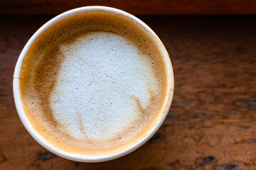 Close Up of Paper cup Coffee take-away, top view. Wooden table and place for text.