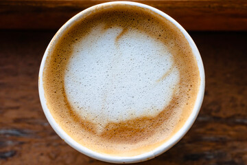 Close Up of Paper cup Coffee take-away, top view. Wooden table and place for text.