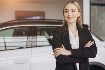 Young smiling woman consultant in show room standing near car with copy space