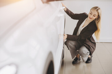 Happy woman customer female buyer client in suit at car chooses auto wants to buy new automobile in showroom vehicle salon dealership store motor show indoor