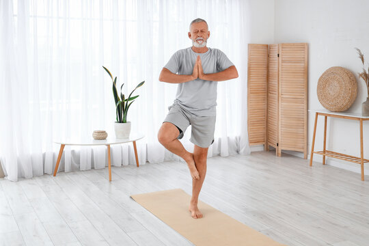 Sporty mature man doing yoga at home
