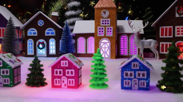 Christmas in motion small Christmas houses among fir trees against the background of large Christmas houses with a chapel