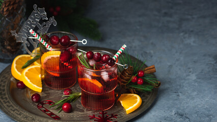 Cranberry boozy Christmas cocktail with ice and rosemary on dark background. Festive spiced drink...