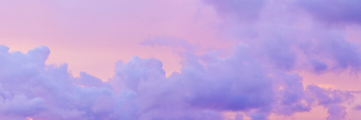 Aesthetic Pastel Sunset, violet fluffy clouds on pink peach colored sky, dreamy cloudscape pastel tones, surreal dreamscape at sunset, soft colorful heaven, wide banner, panoramic view.