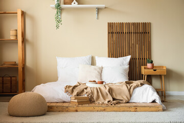 Interior of stylish bedroom with breakfast on bed and books
