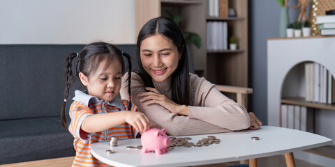 Mother Teaching Daughter Financial Responsibility with Piggy Bank