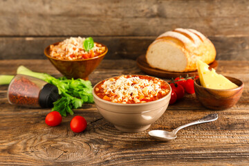 Bowls of pasta fagioli with ingredients on wooden background