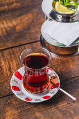 Freshly brewed black Turkish tea with sweetener and lemon slice on wooden table