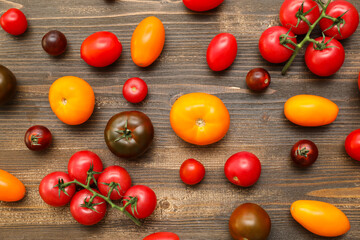 Different fresh tomatoes on wooden background