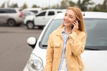 Mature woman talking by mobile phone near car outdoors