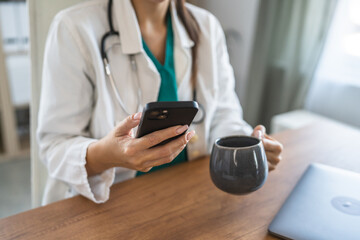 close up of woman doctor use mobile phone and drink coffee on break