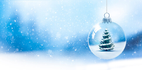 Weihnachtskugel aus Glas vor verschneiter Landschaft