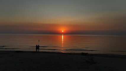 Serene beach sunset with silhouettes.