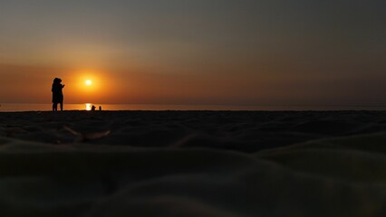 Beach sunset silhouette with orange sky.