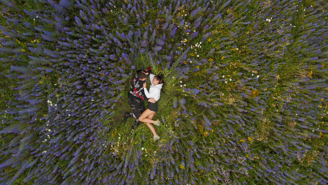 Couple enjoying a serene moment in a lush purple flower field - Powered by Adobe