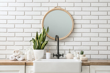 Sink and bath accessories near white brick wall in bathroom