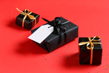 Black gift boxes and confetti on red background
