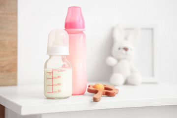 Bottles of baby milk formula and toys on light table at home