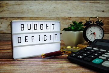 BUDGET DEFICIT letterboard text on LED Lightbox on wooden background, Business and Finance concept background