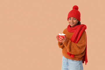 Cute African-American girl in stylish red hat and knitted scarf with cup of hot cocoa on brown...