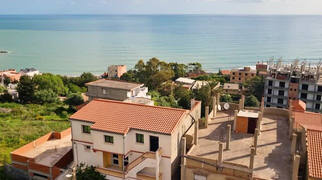View of village houses and construction sides in Azeffoun region of North Algeria with Meditereanian sea in the background on a sunny morning