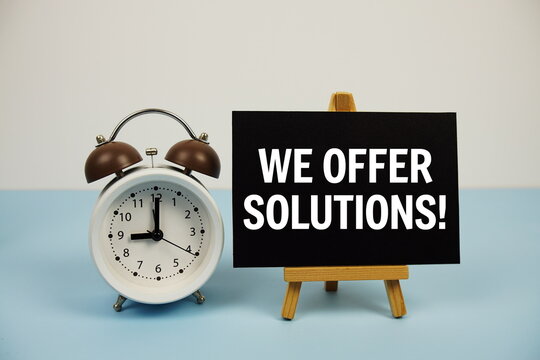 We offer solutions text on paper card with alarm clock on blue background