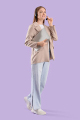 Female technical support agent in headset with laptop walking on lilac background