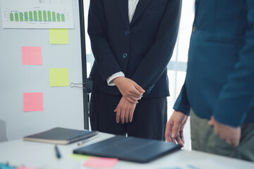 Strategic Business Discussion: Two business professionals stand near a whiteboard during a serious meeting, reviewing data and sticky notes.